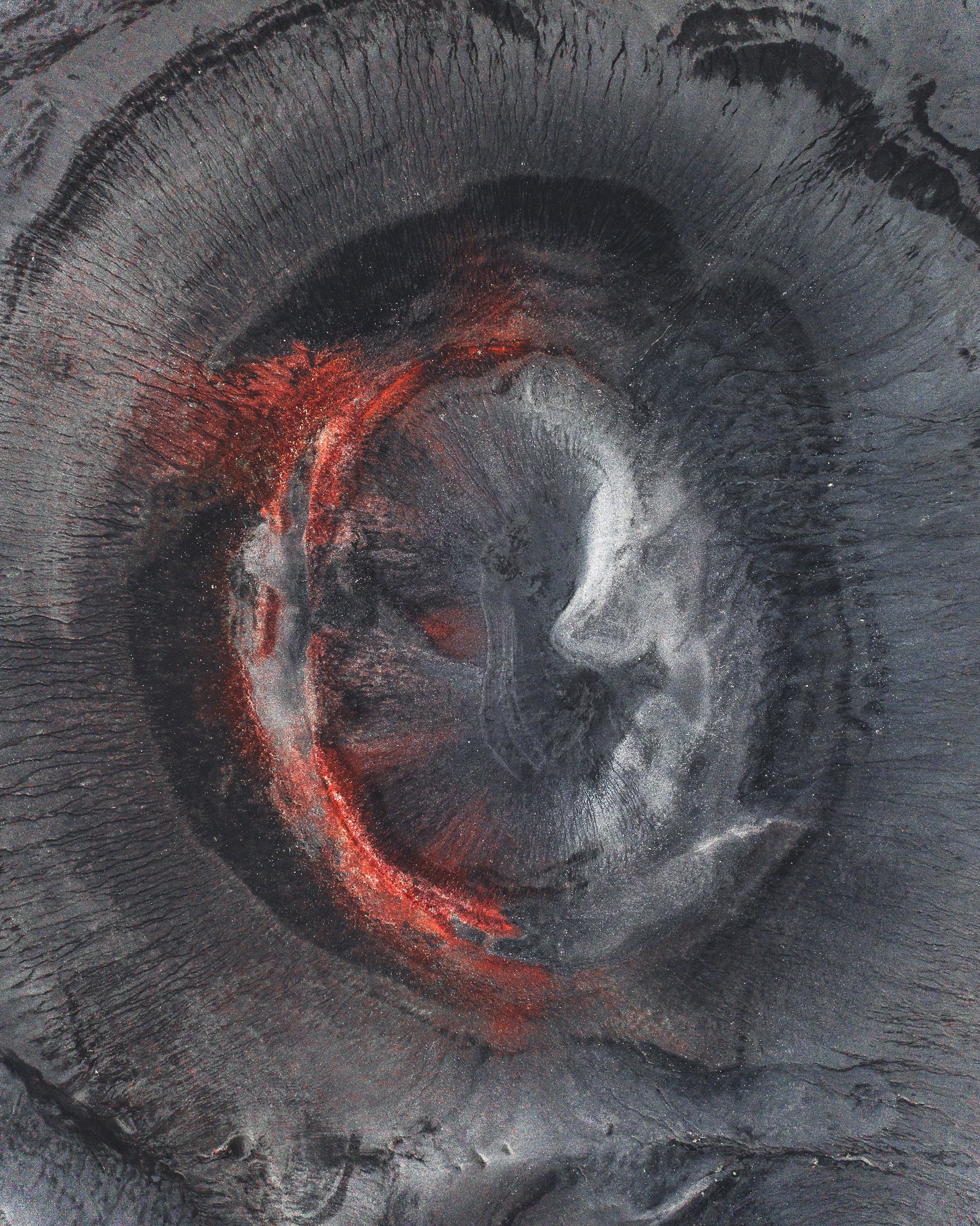 Close-up of a volcanic crater with red hot material at the center