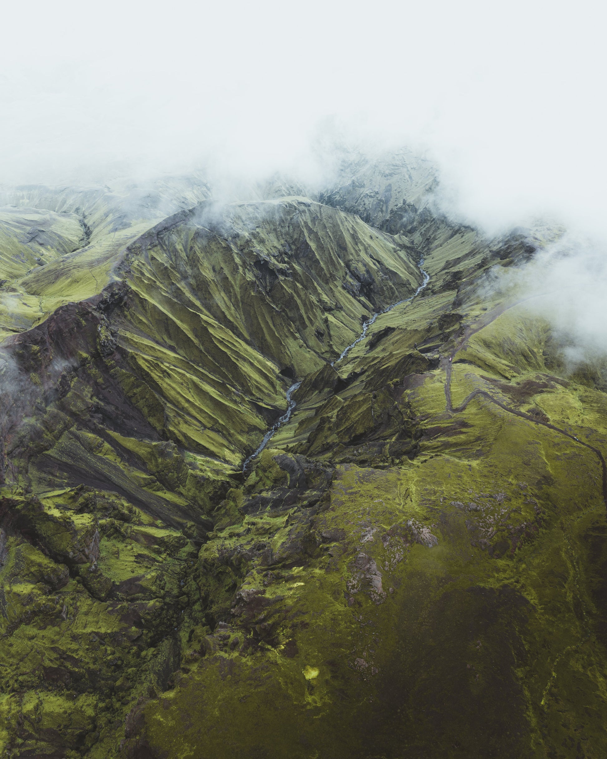 Aerial view of a mountainous landscape with green terrain and clouds.