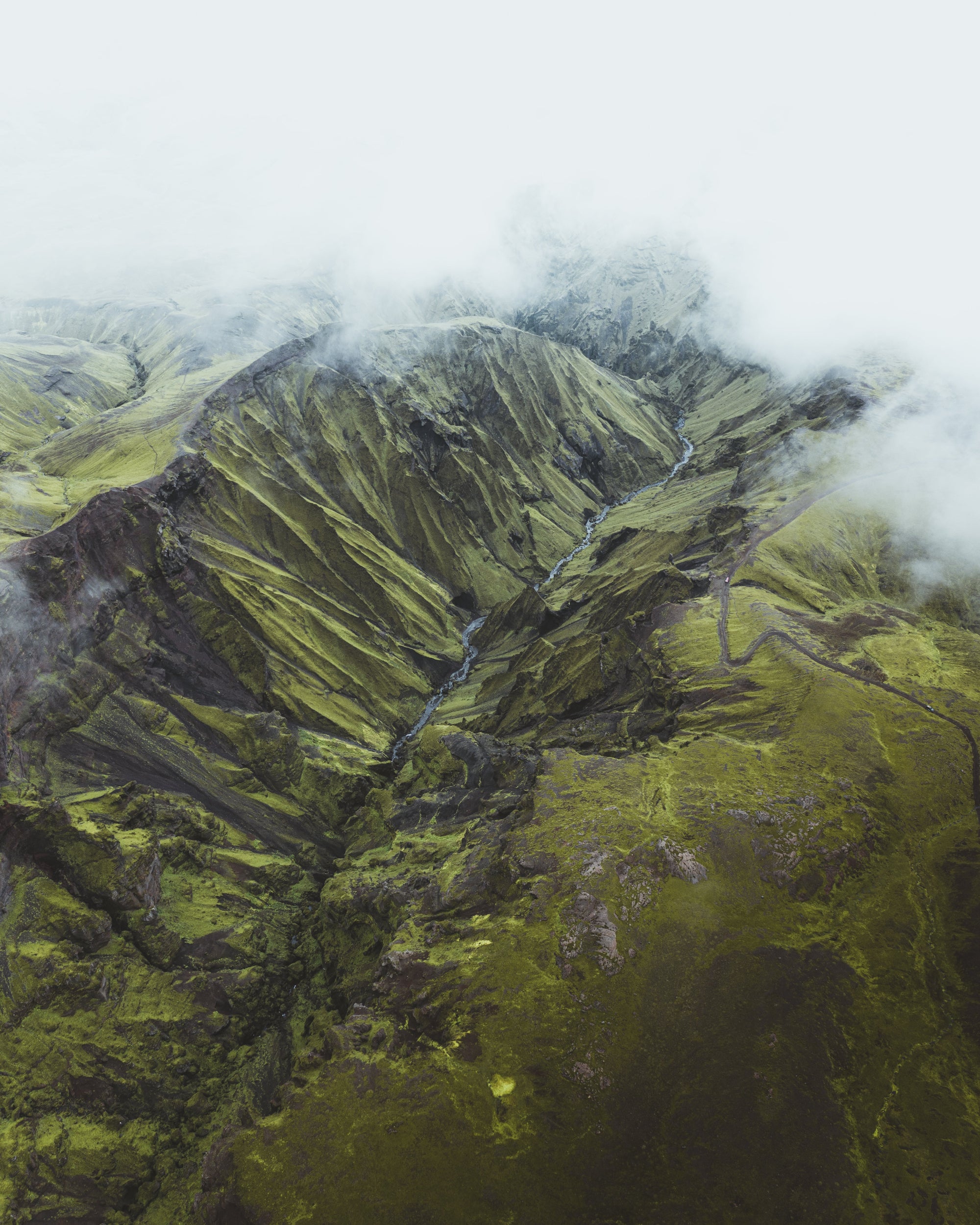 Aerial view of a mountainous landscape with green terrain and clouds.