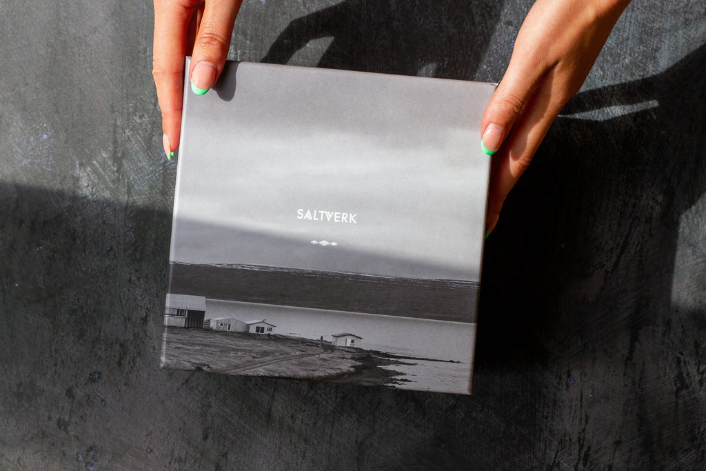 Person holding a book titled 'Saltwater' on a dark surface
