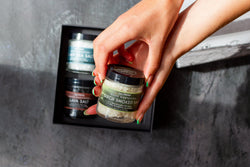 Hand holding a jar of black smoked salt with a blurred background