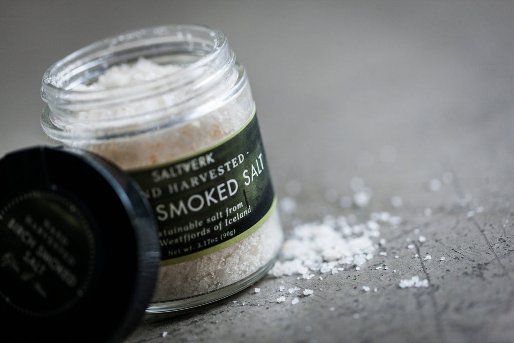 Jar of smoked salt with a label on a gray surface