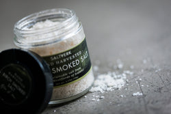 Jar of smoked salt with a label on a gray surface